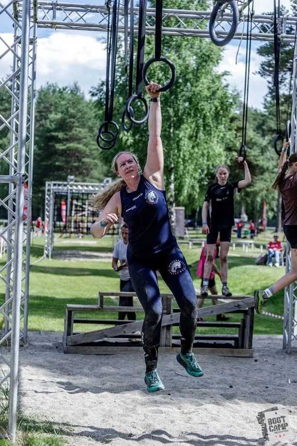 Løper strekker seg etter ringene i riggen under Bootcamp Survivor