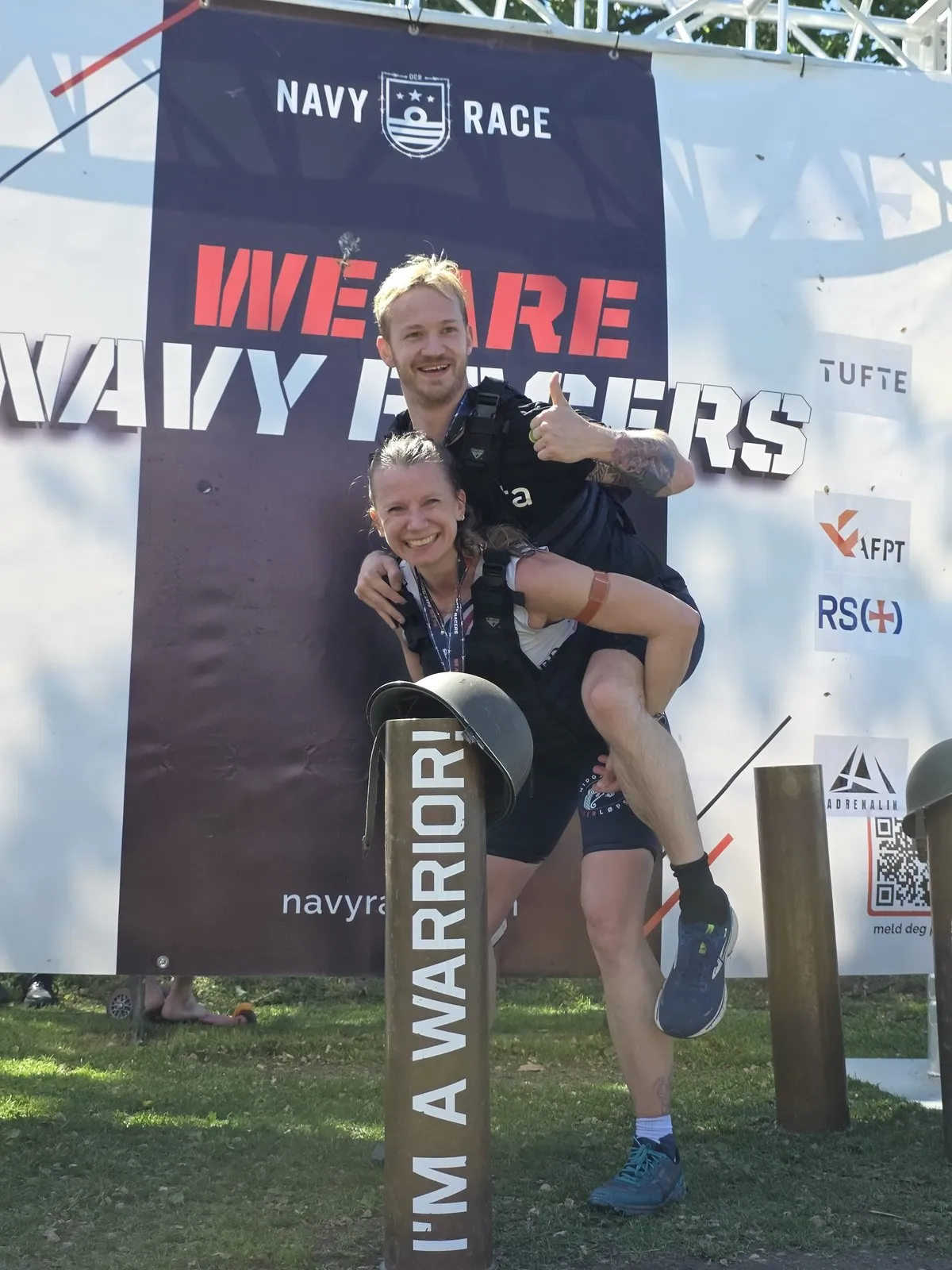 To Midgard-løpere feirer foran NavyRace-veggen etter målgang